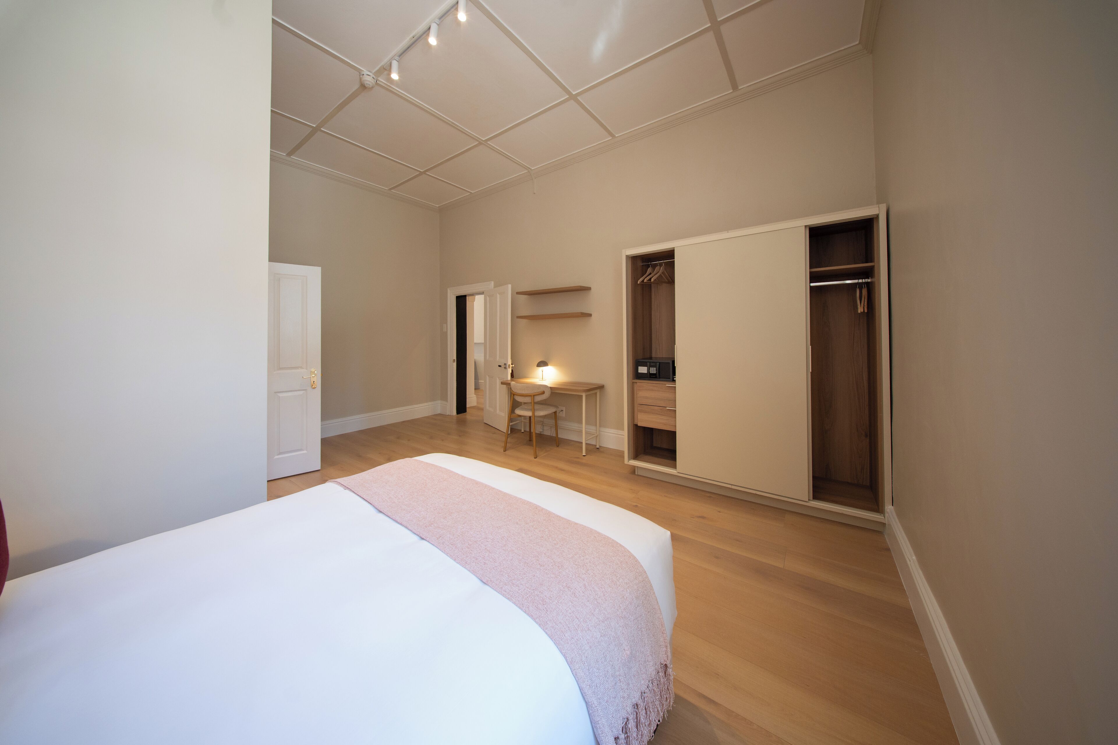 A bedroom with a bed, a desk, and a walk-in closet.