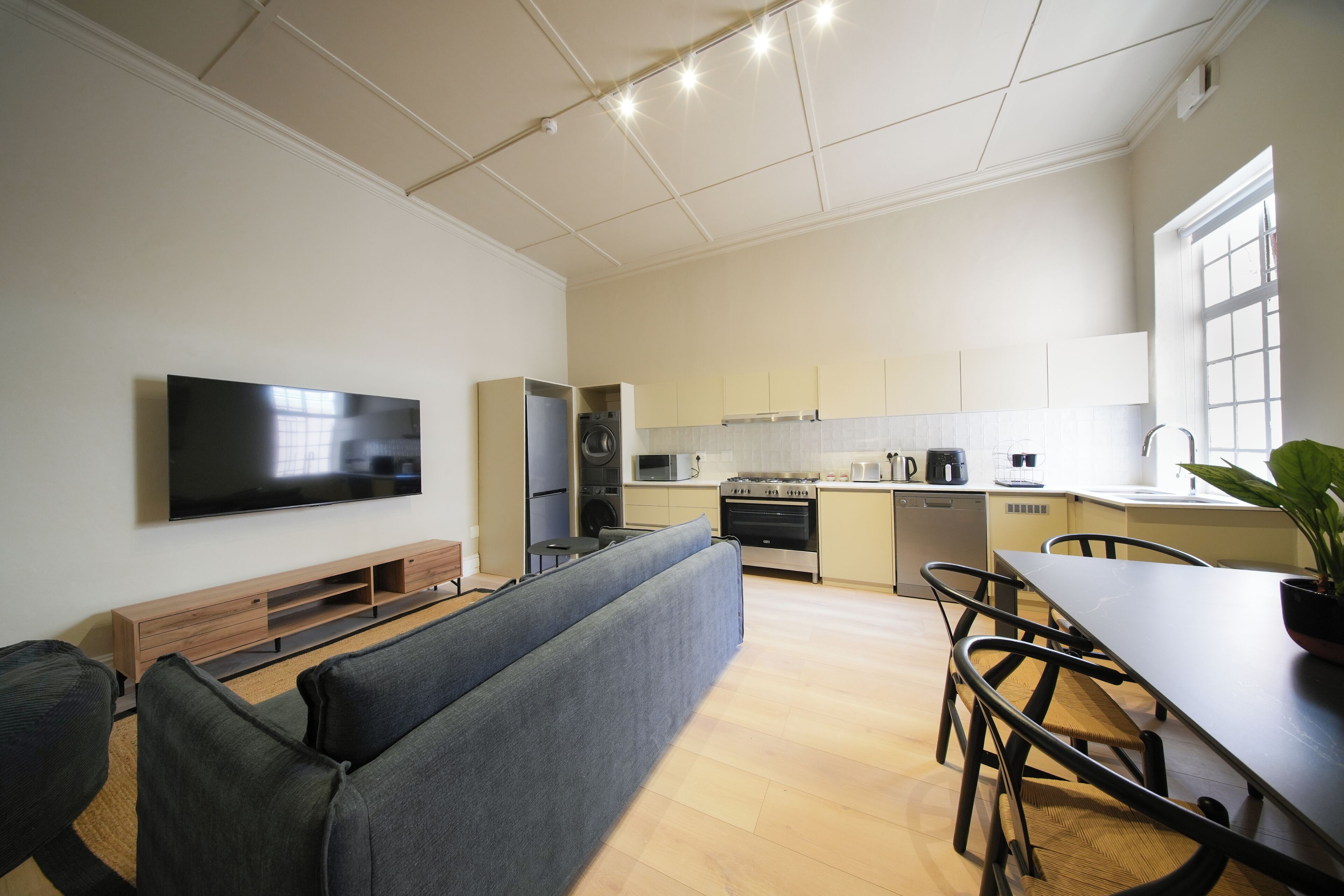 A modern kitchen with a dining area, built-in appliances, and a flat-screen TV.