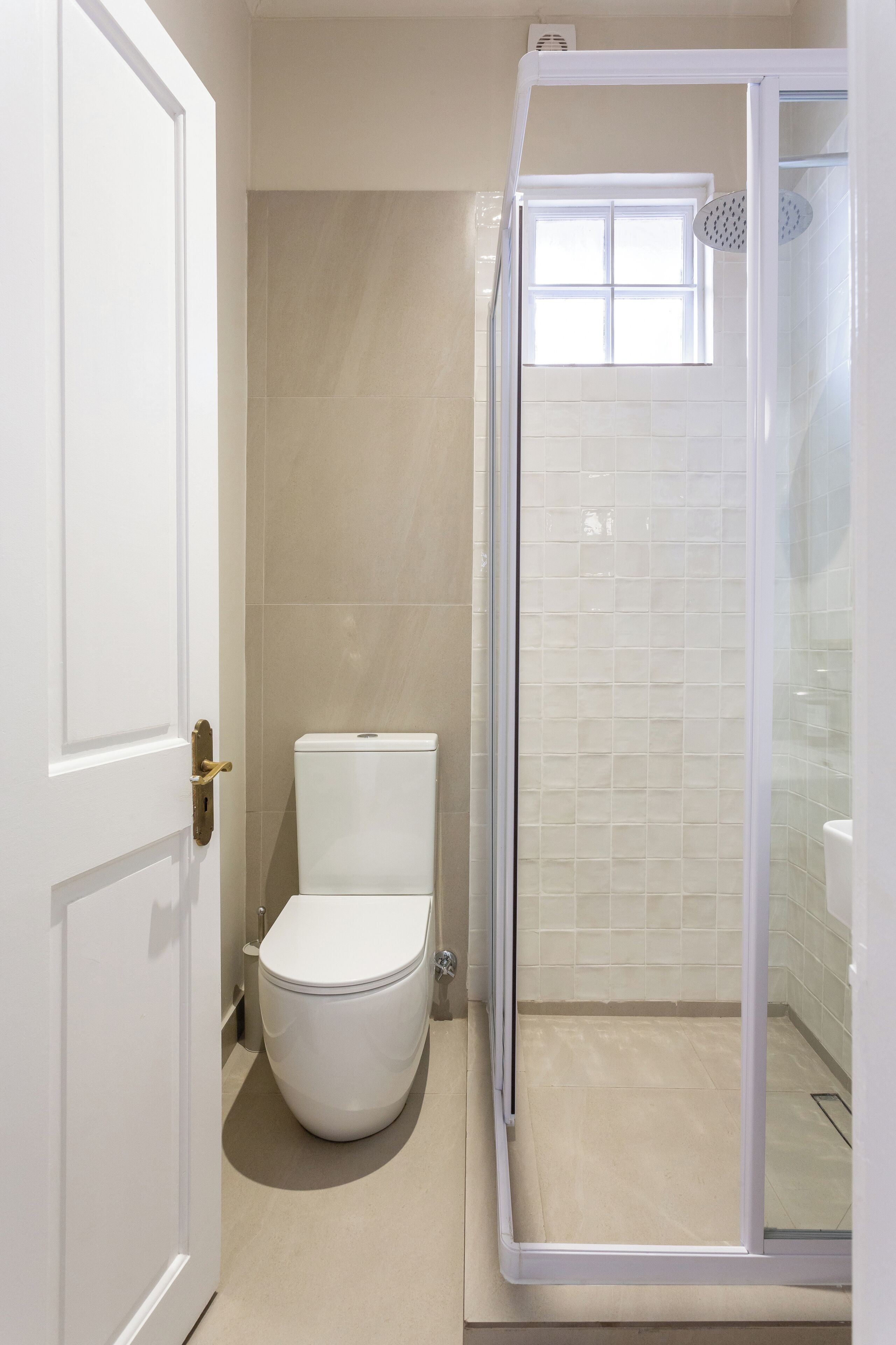 A bathroom with a toilet, a shower enclosure, and a door.