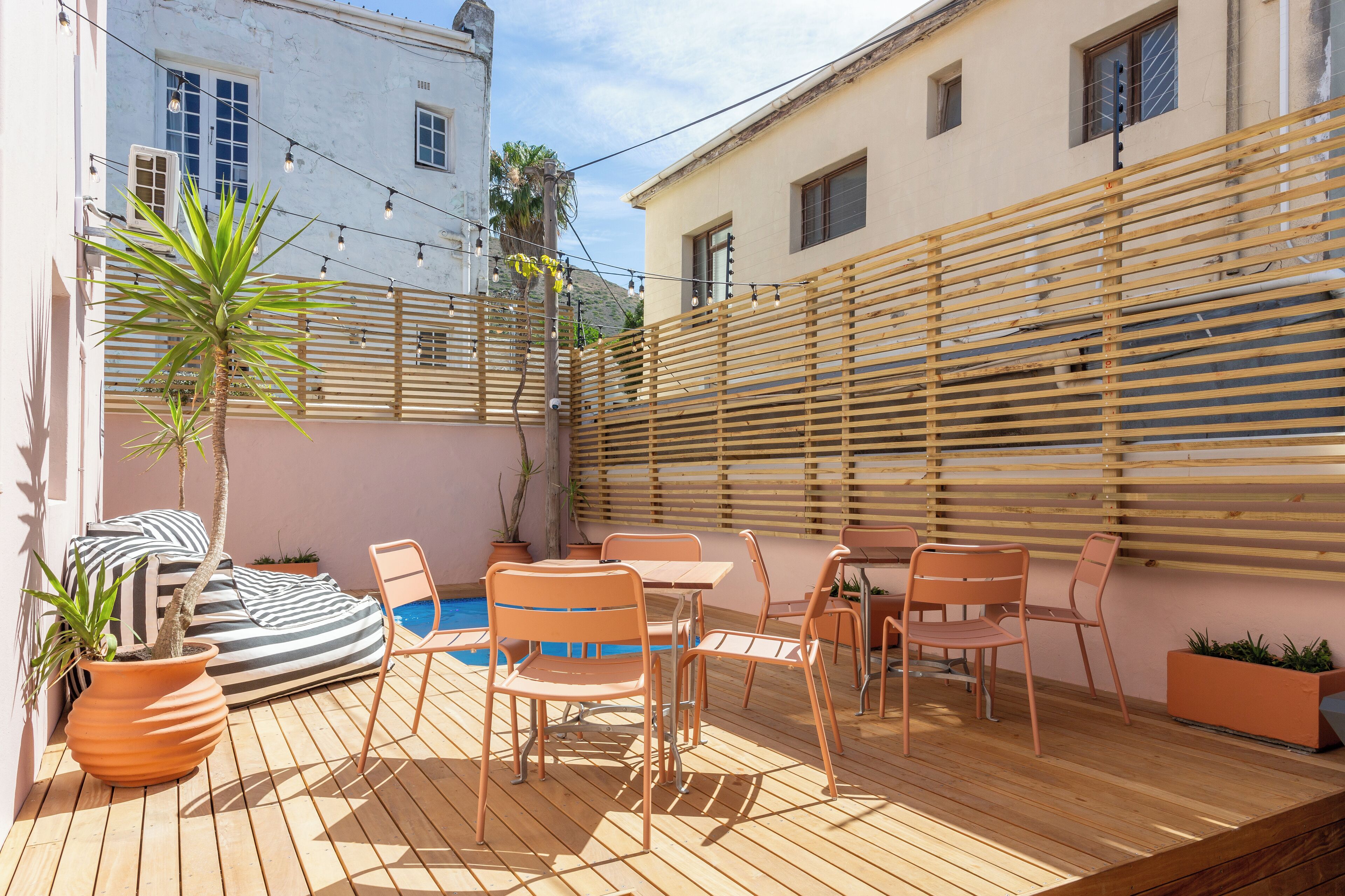 Une terrasse en bois avec des meubles d’extérieur, une piscine et une clôture en bois.