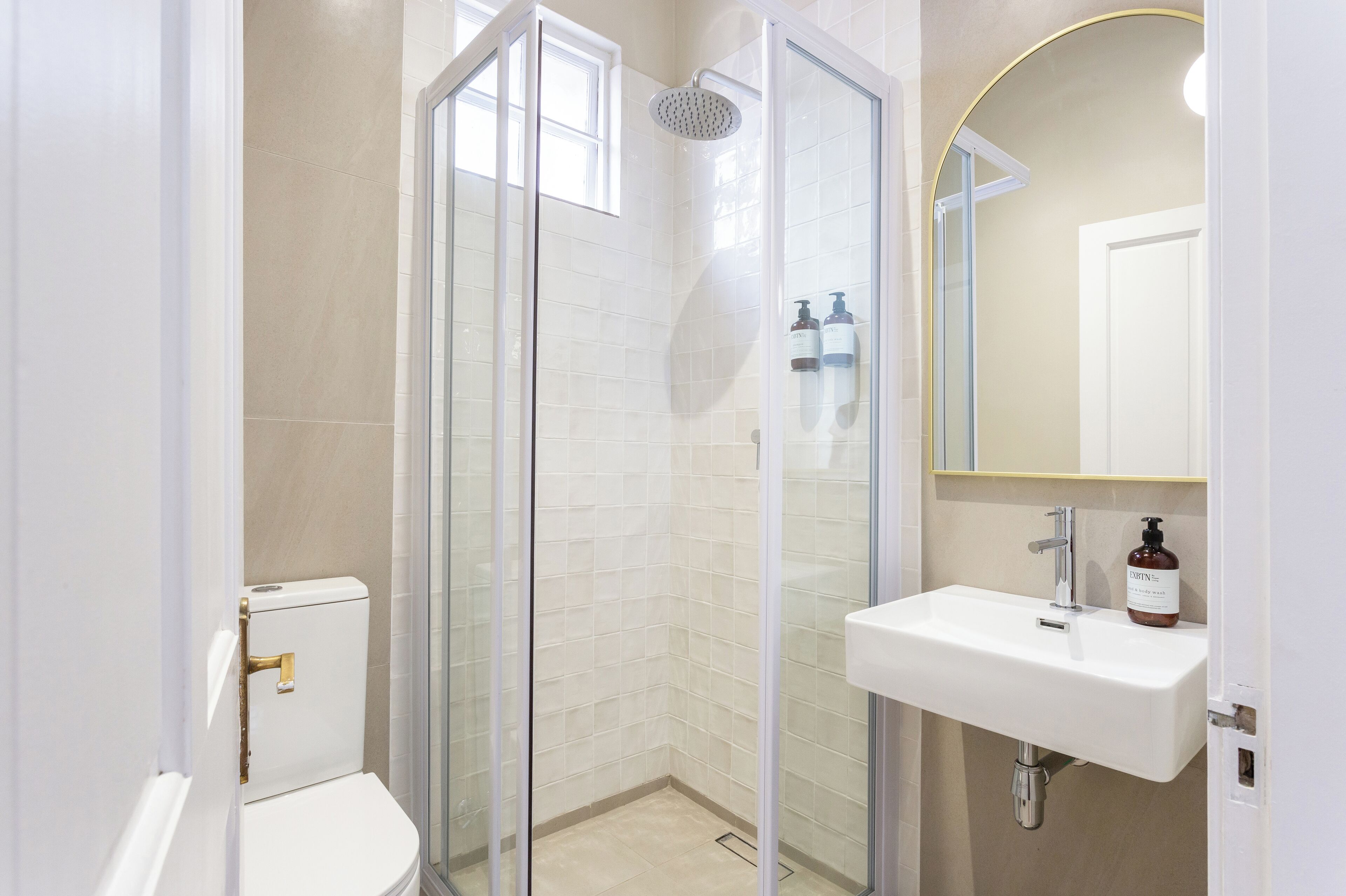 A modern bathroom with a glass-enclosed shower, a white sink, and a toilet.