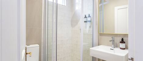 A modern bathroom with a glass-enclosed shower, a white sink, and a toilet.