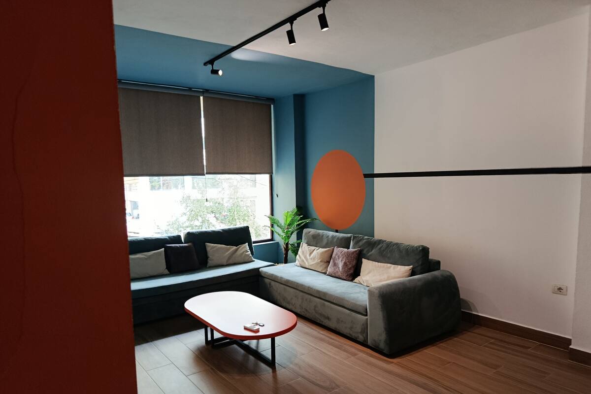 Un salon moderne avec un canapé, une petite table et une grande fenêtre.