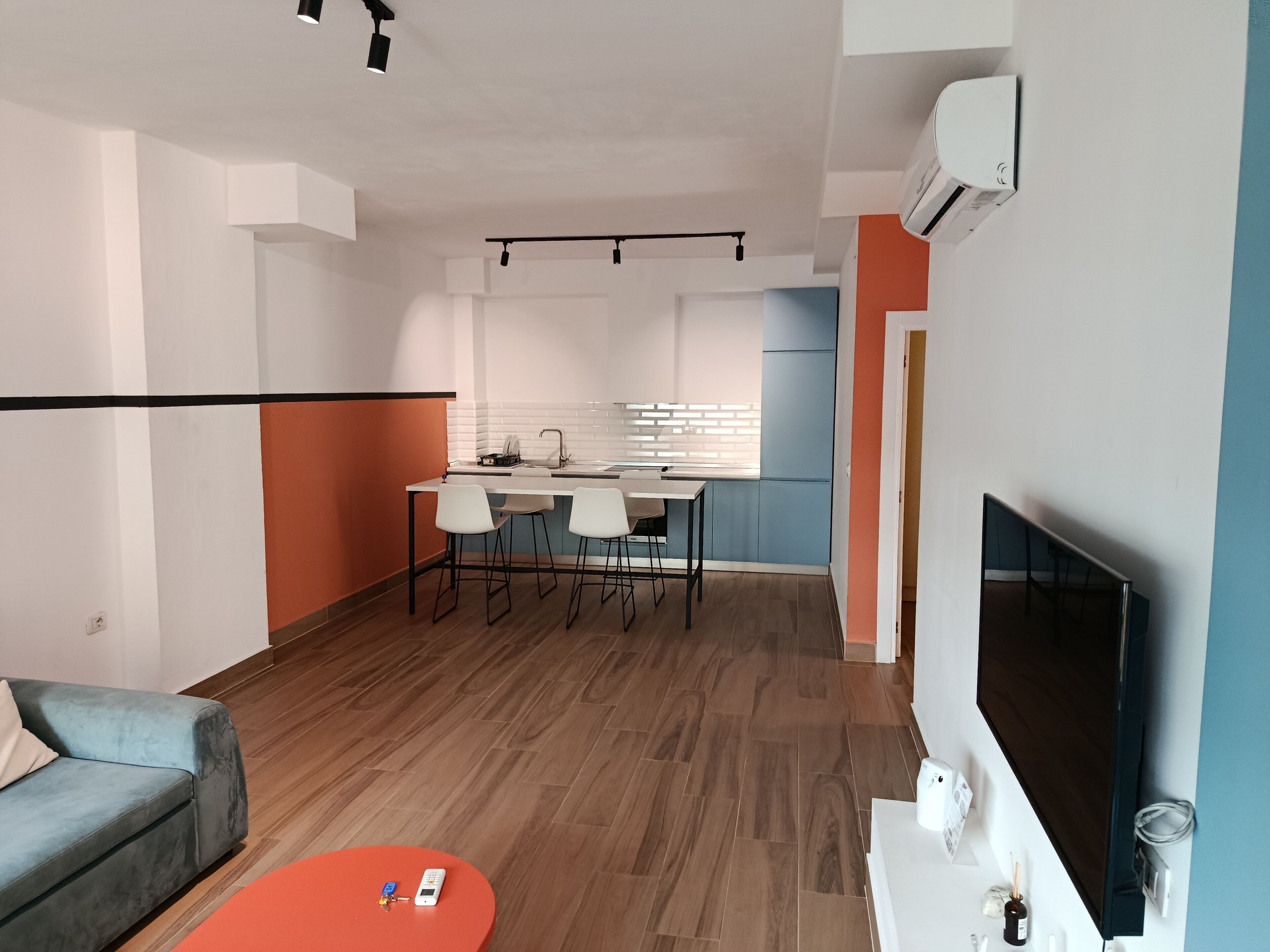 Een moderne woonkamer met een bank, een salontafel, een televisie en een keuken op de achtergrond.
