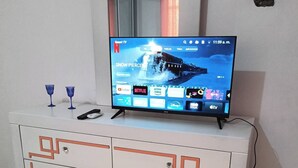 Un mueble blanco de entretenimiento con un televisor de pantalla plana mostrando la interfaz de un servicio de streaming.