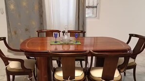 Una mesa de comedor con seis sillas, una botella de vidrio decorativa y dos vasos azules.