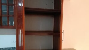 Ein Holzkabinent mit mehreren Regalen, einer Arbeitsplatte und einem Mülleimer.