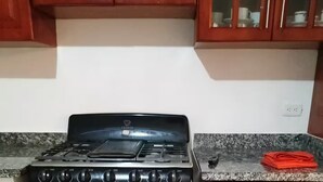 Una cocina con estufa negra, encimera de granito y armarios de madera.
