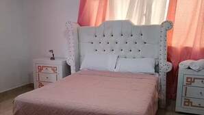 Ein Schlafzimmer mit Bett, Nachttischen, einer Klimaanlage und Vorhängen.