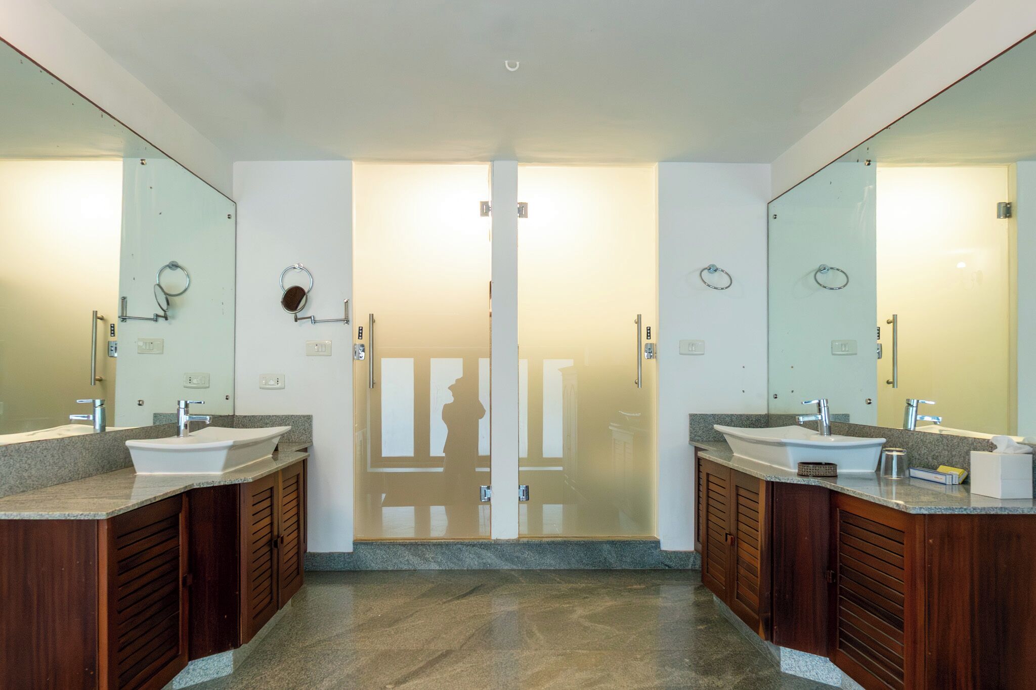 A modern bathroom with two sinks, wooden cabinets, and large mirrors.