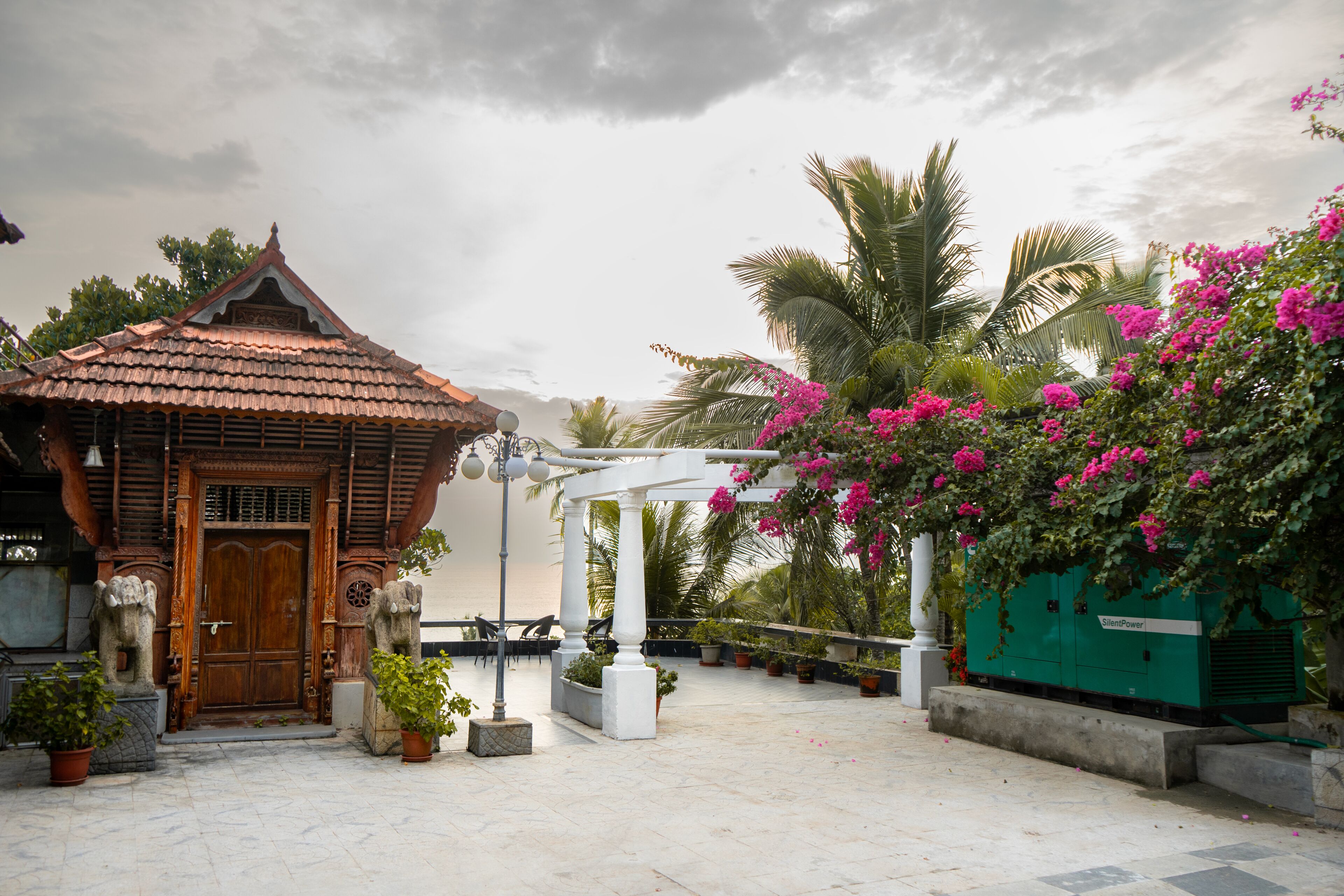 A traditional building with a tiled roof, a wooden door, and a white column structure in the background.