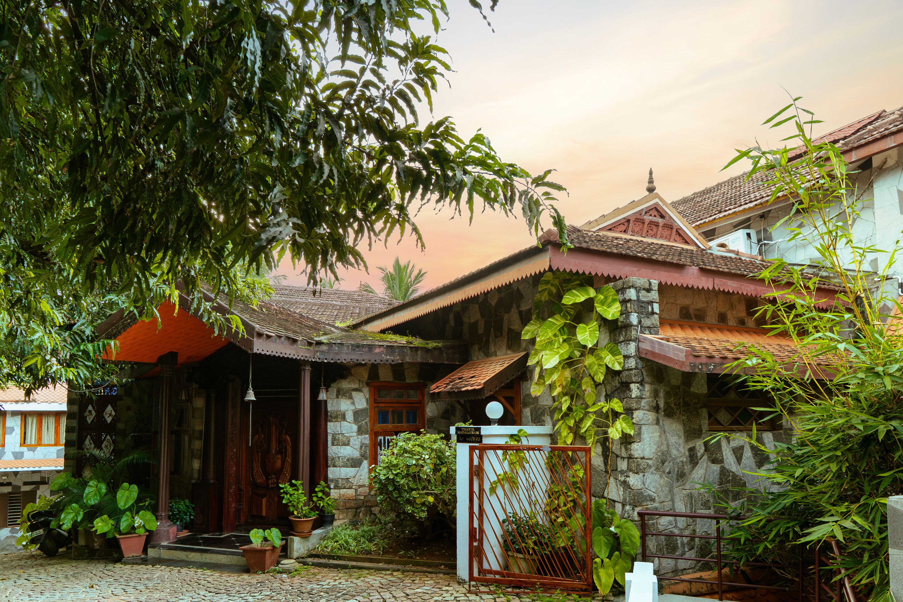 A traditional house with a stone facade, a tiled roof, and a gated entrance.