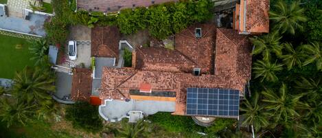 An aerial view of a residential area with a swimming pool, solar panels, and lush greenery.