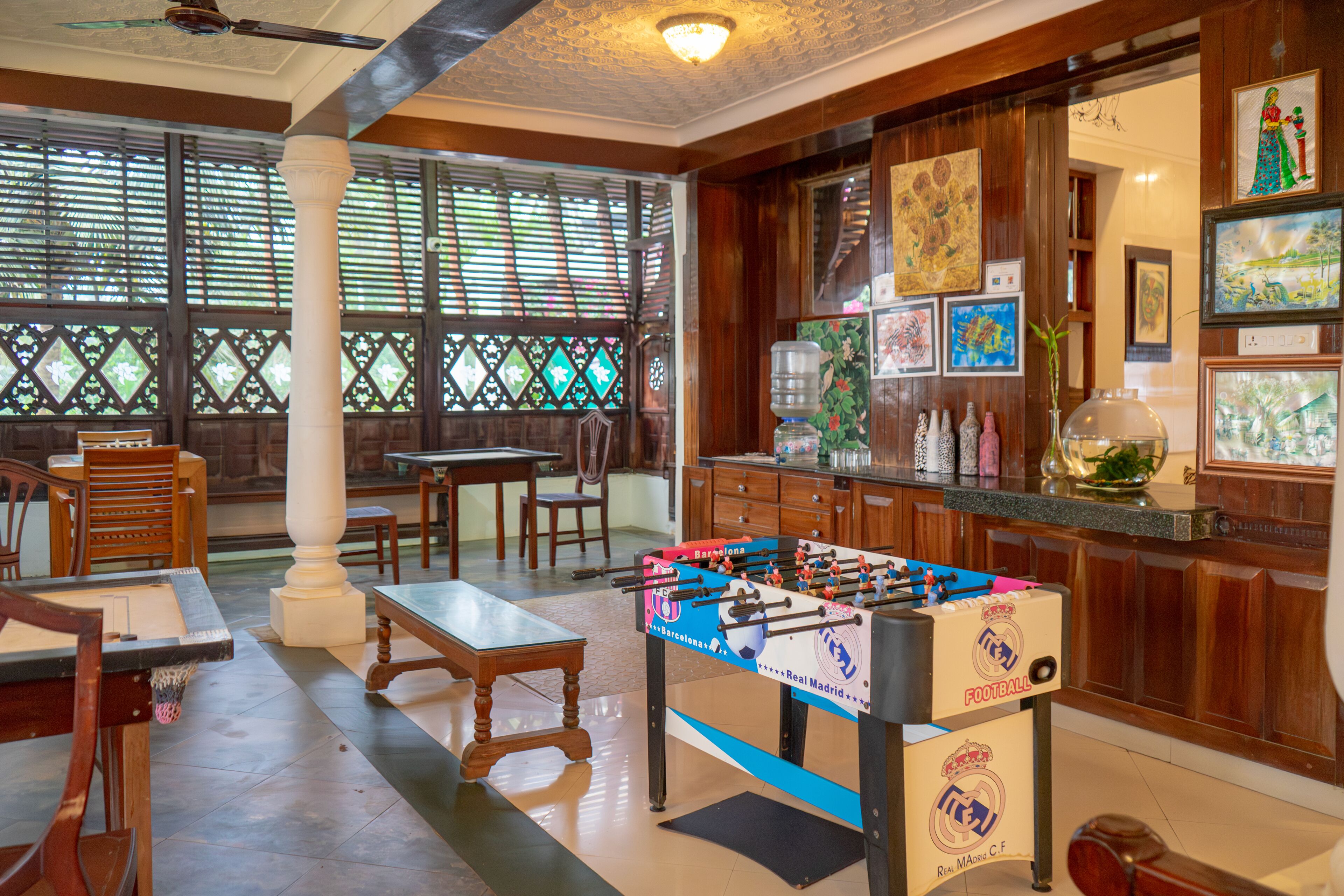 A room with a foosball table, wooden furniture, and artwork on the walls.