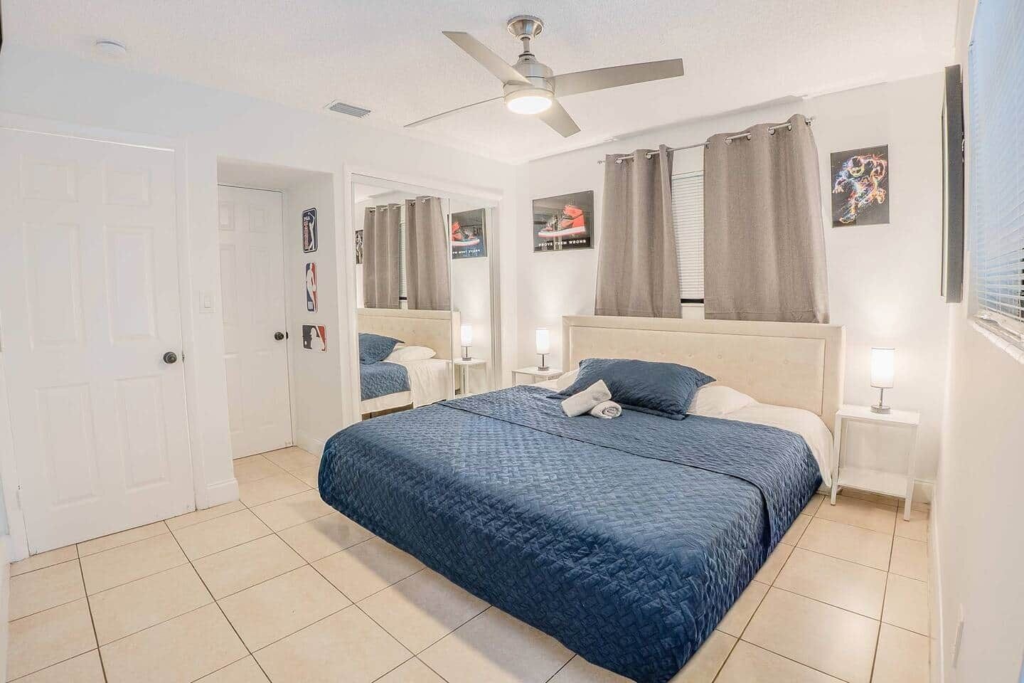Une chambre à coucher comprenant un lit, un ventilateur de plafond, une table de chevet et un miroir fixé au mur.