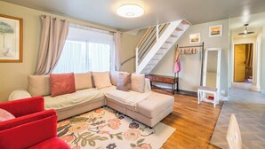 Un salon moderne avec un canapé d’angle, une petite table et un escalier menant à un niveau supérieur.
