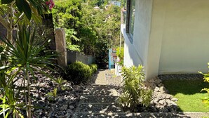 A pathway leading to a house with a thatched roof, surrounded by lush greenery and a view of the sea. - Villa JuPITER, Boracay, ocean view holiday home with pool (Malay)