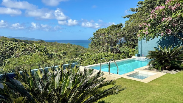 A pool with a view of the ocean, surrounded by lush greenery and a clear sky. - Villa JuPITER, Boracay, ocean view holiday home with pool (Malay)