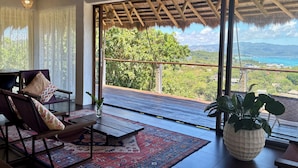 A room with a large window, a wooden ceiling, a patterned rug, and a potted plant. - Villa JuPITER, Boracay, ocean view holiday home with pool (Malay)