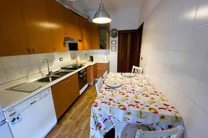 A compact kitchen with wooden cabinets, a white countertop, and a dining table set for four.