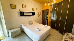 Ein Schlafzimmer mit Bett, Nachttisch, Kleiderschrank und Wandregal.