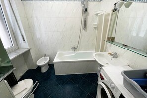 Ein Badezimmer mit Toilette, Bidet, Badewanne, Waschbecken und einer Waschmaschine.