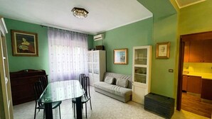 Ein Essbereich mit Tisch und Stühlen, einer Couch und einer Küchenzeile mit Schränken.