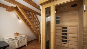 Eine Holzsauna mit Glastür, einer Holztreppe und einem weißen Schrank mit Schubladen.