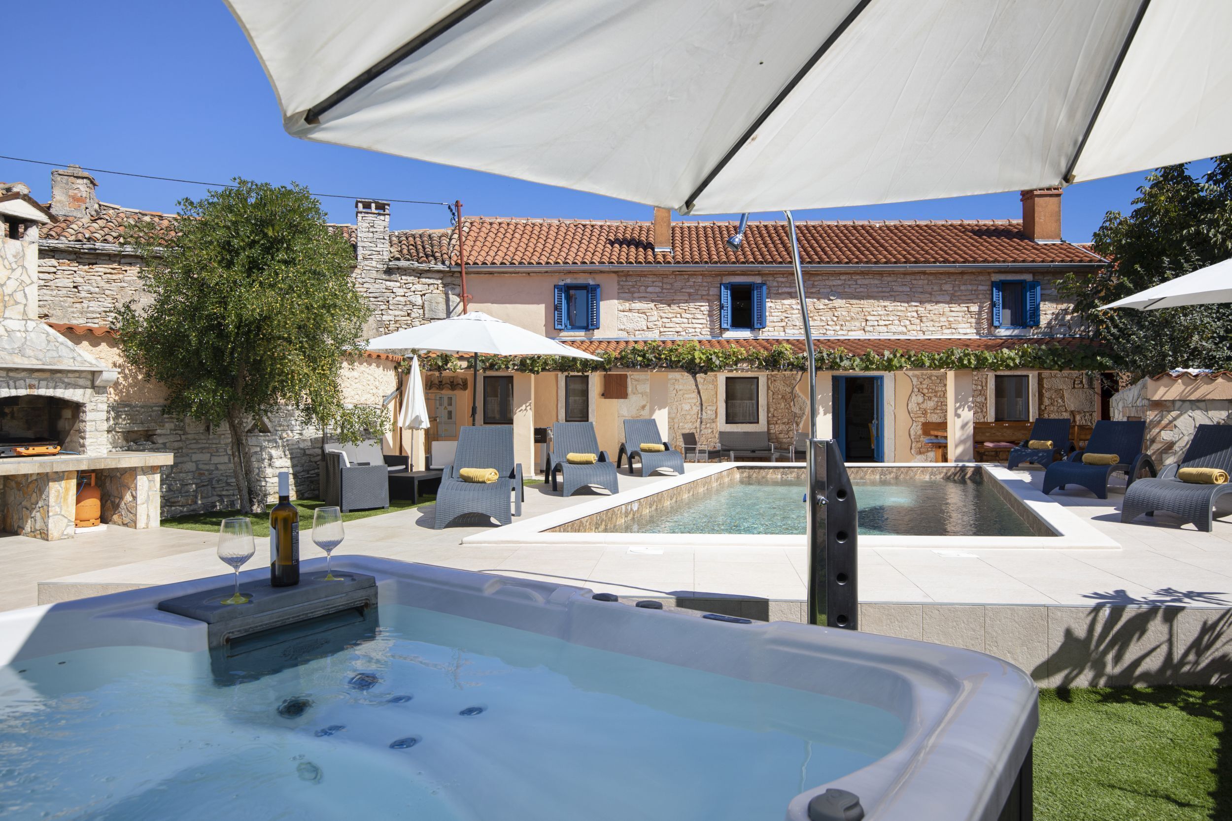 A pool area with lounge chairs and a hot tub.