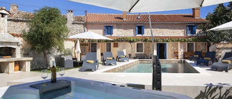 A pool area with lounge chairs and a hot tub.