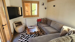 Un salón acogedor con techo de madera, un sofá, una mesa de centro y una alfombra de cuadros.