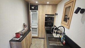 Una cocina compacta con armarios de madera, una encimera negra y un horno empotrado.