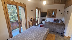 Una habitación con cama, escritorio, silla, sofá y mesa de comedor. Hay dos ventanas y una puerta.