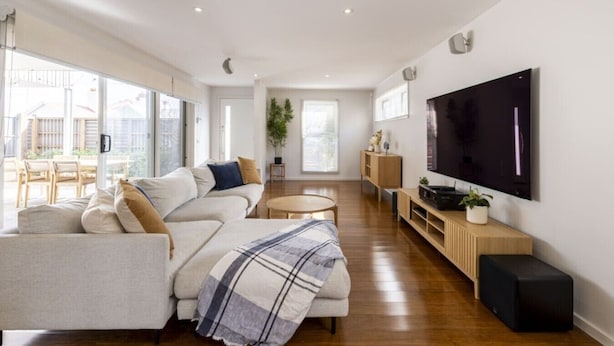 A modern living room with a sofa, a coffee table, a TV, and a wooden cabinet. - Modern 3BR Executive Townhouse in CBD, Mibnb (Geelong)