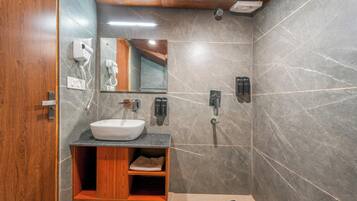 A modern bathroom with a wooden vanity, a white sink, a mirror, a handheld showerhead, and a wall-mounted phone.