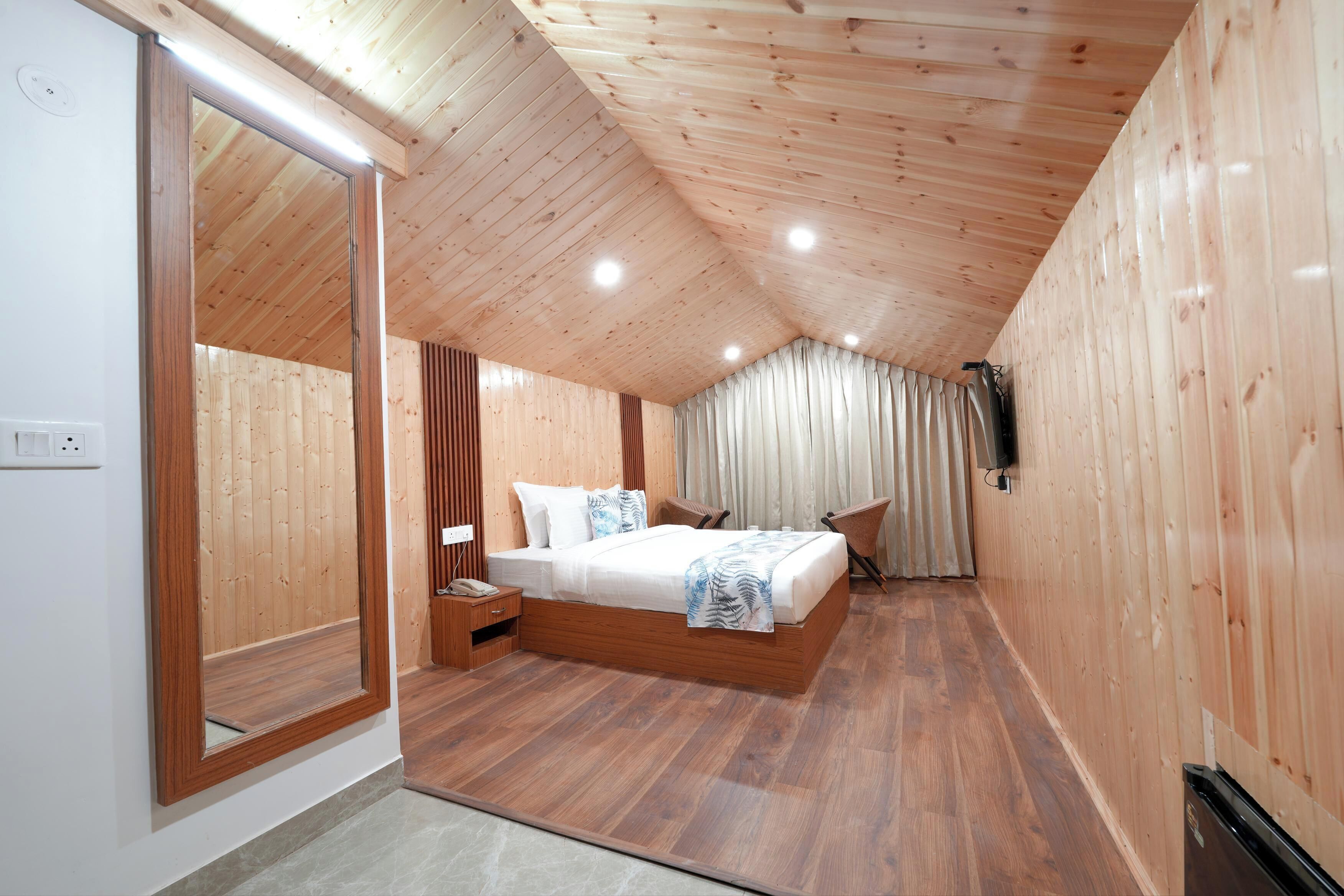 A bedroom with a wooden ceiling, a large bed, a nightstand, a chair, and a curtain.