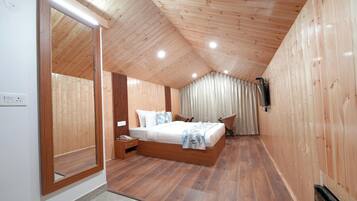 A bedroom with a wooden ceiling, a large bed, a nightstand, a chair, and a curtain.