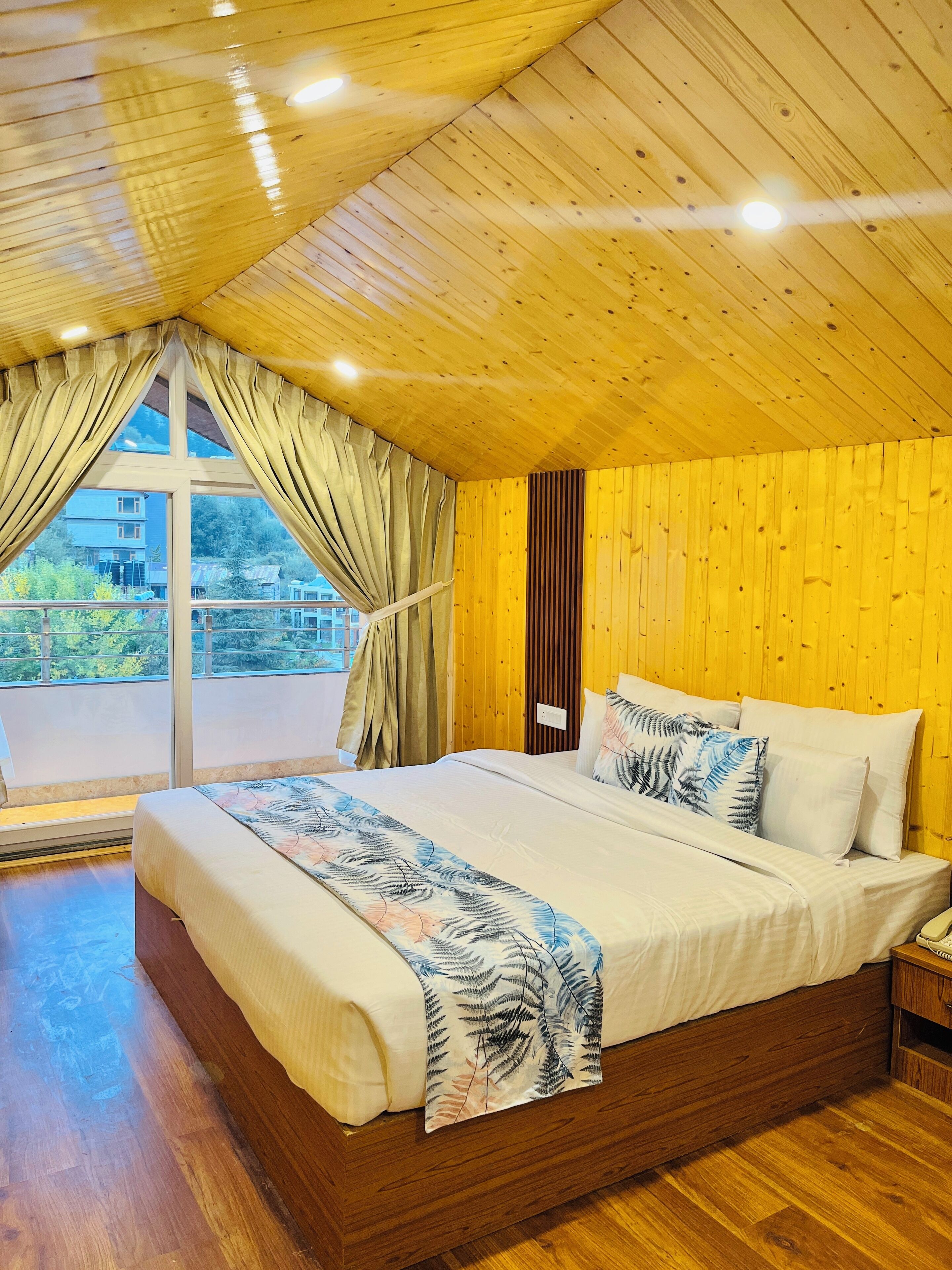 Un dormitorio amplio con una cama grande, techo de madera y vistas al exterior.