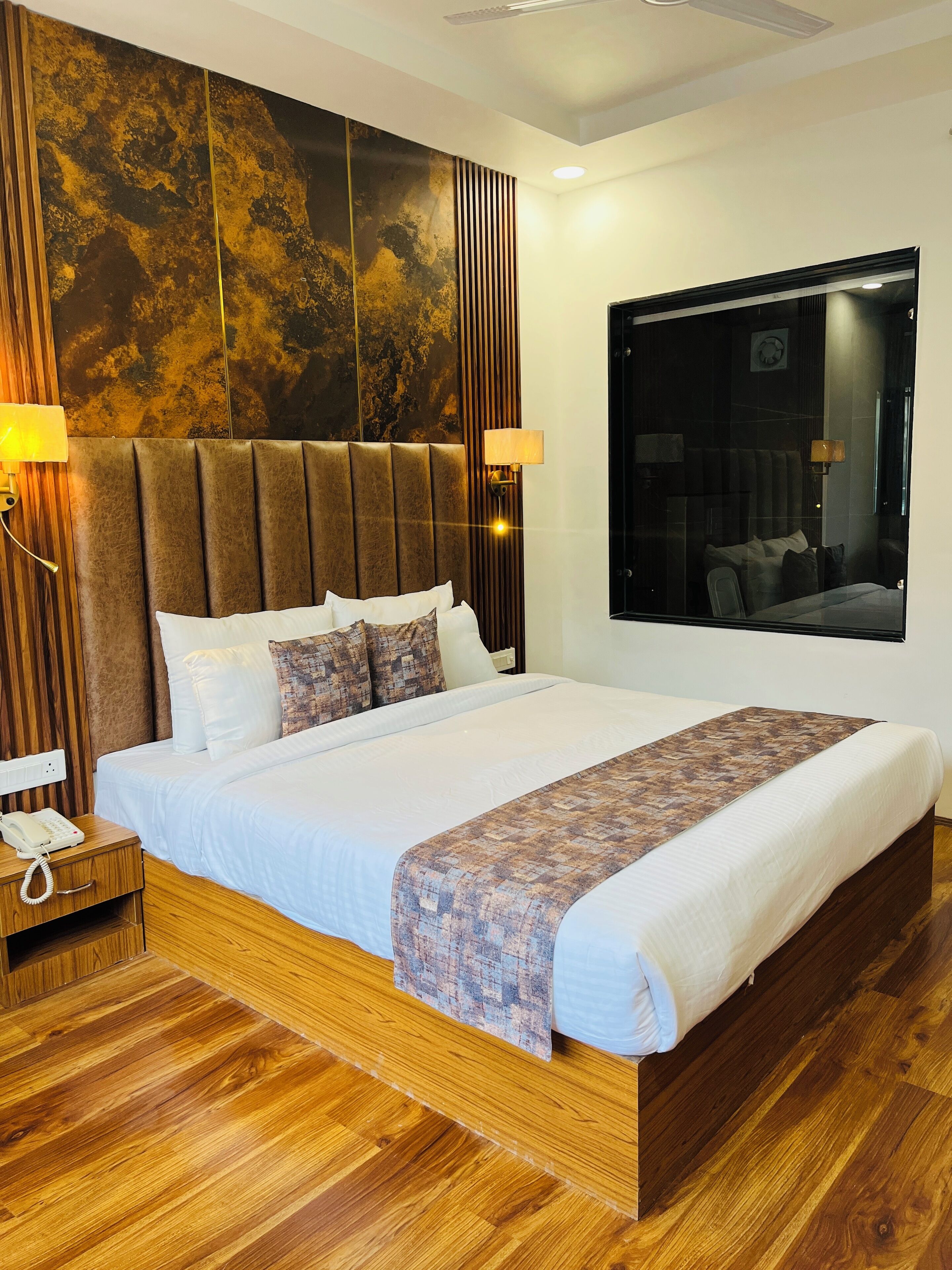 Habitación de hotel moderna con una cama grande, cabecera de madera y un amplio ventanal.