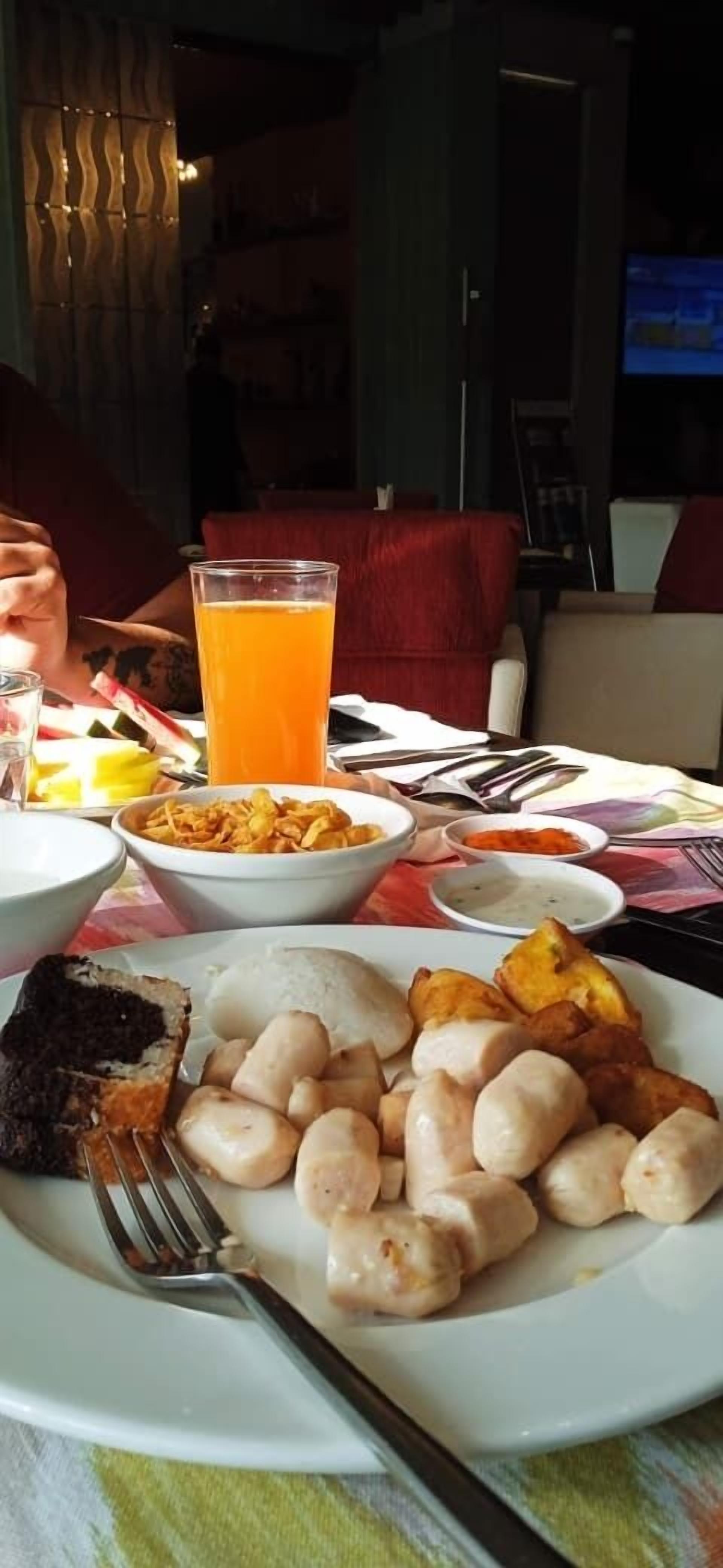 A dining table with a meal consisting of rice, fried items, and a glass of orange juice.