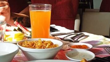 A dining table with a meal consisting of rice, fried items, and a glass of orange juice.