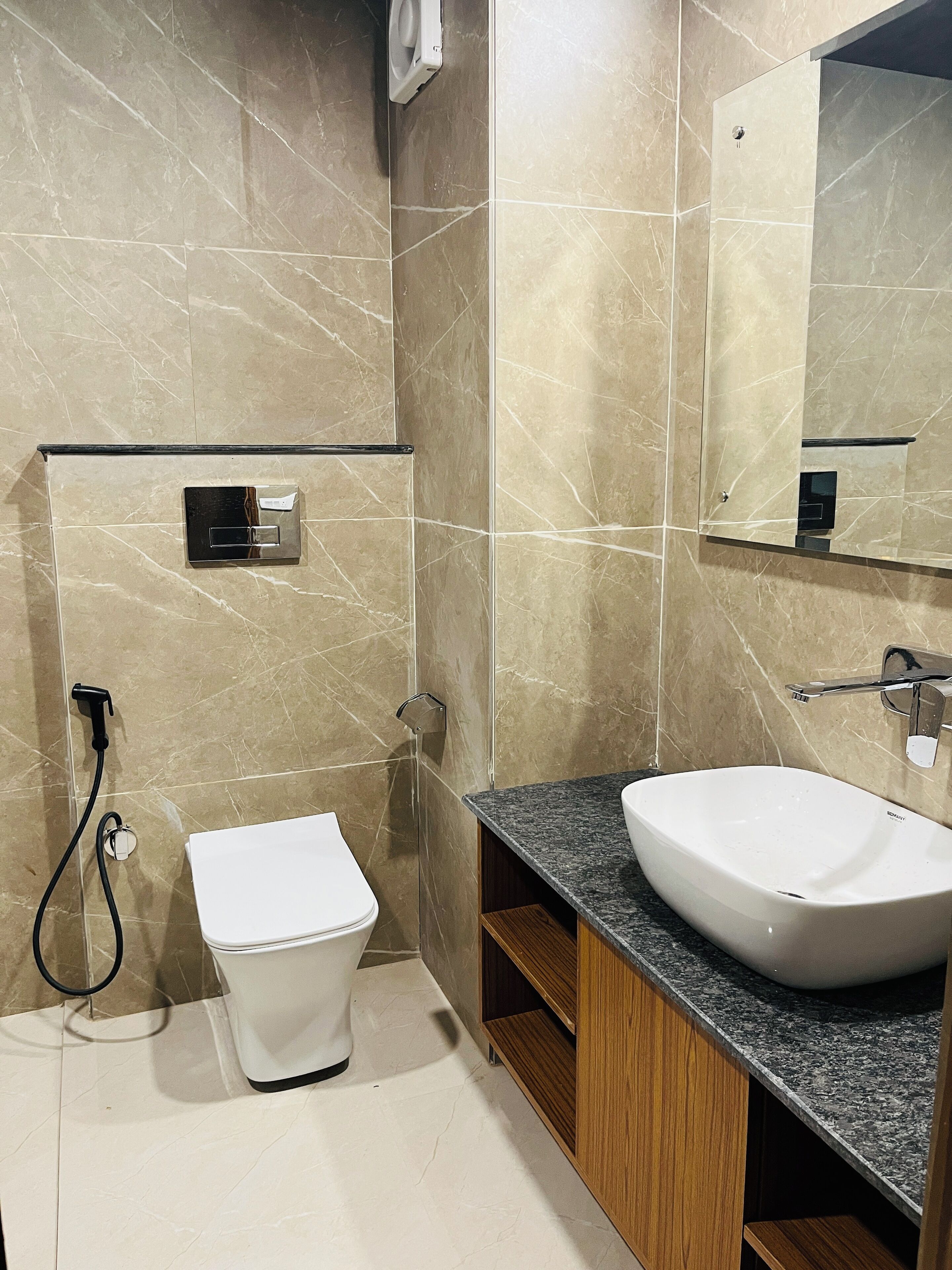 Un baño moderno con inodoro blanco, un lavamanos amplio y un espejo.