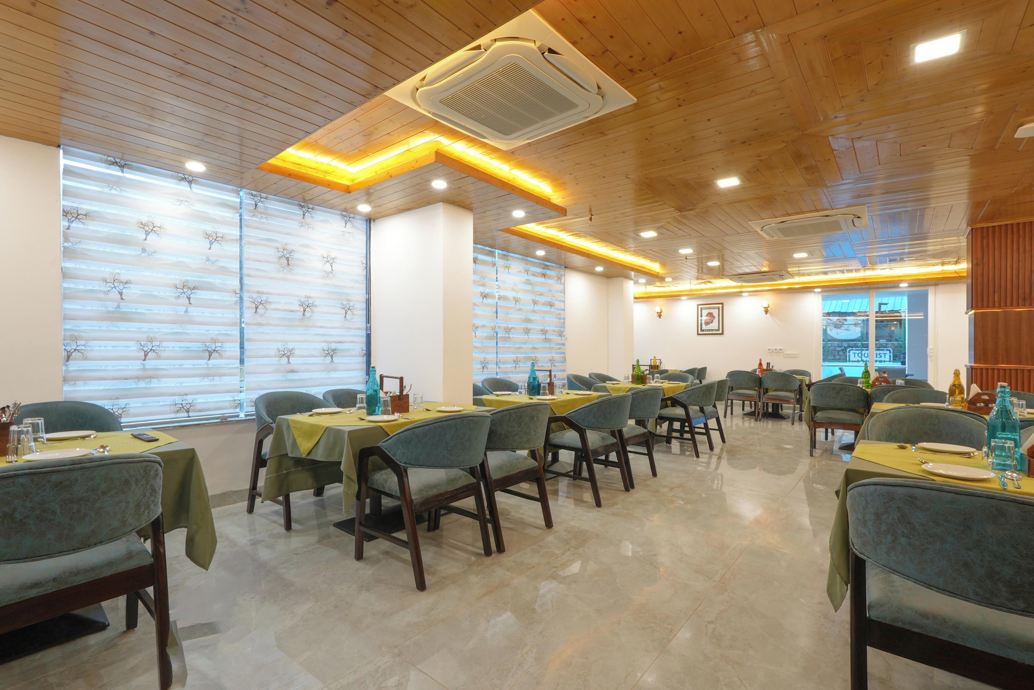 A restaurant with wooden ceiling and walls, tables with yellow tablecloths, and chairs.