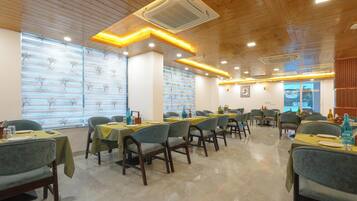 A restaurant with wooden ceiling and walls, tables with yellow tablecloths, and chairs.