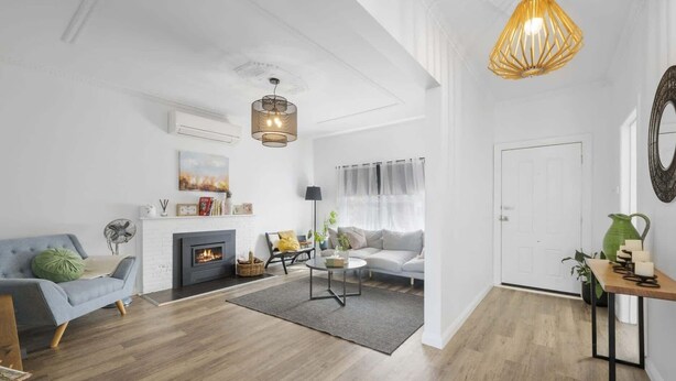Een moderne woonkamer met een open haard, een bank, een salontafel en een eethoek met een tafel en stoelen.