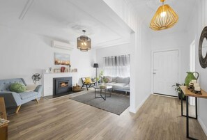 Un salon moderne avec une cheminée, un canapé, une table basse et un coin repas comprenant une table et des chaises.