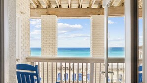 Un balcone con piscina, sedie blu e vista sulla spiaggia e sull'oceano.