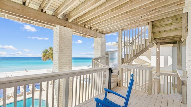 Un terrazzo in legno con vista sull'oceano e una piscina.