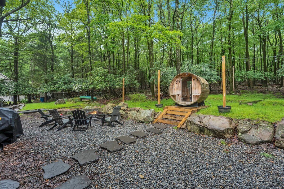 Un área de estar al aire libre de estilo rústico con una estructura circular de madera, escalones de piedra y un camino de grava.