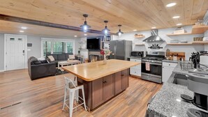 A modern kitchen with wooden cabinets, a central island, and built-in appliances.